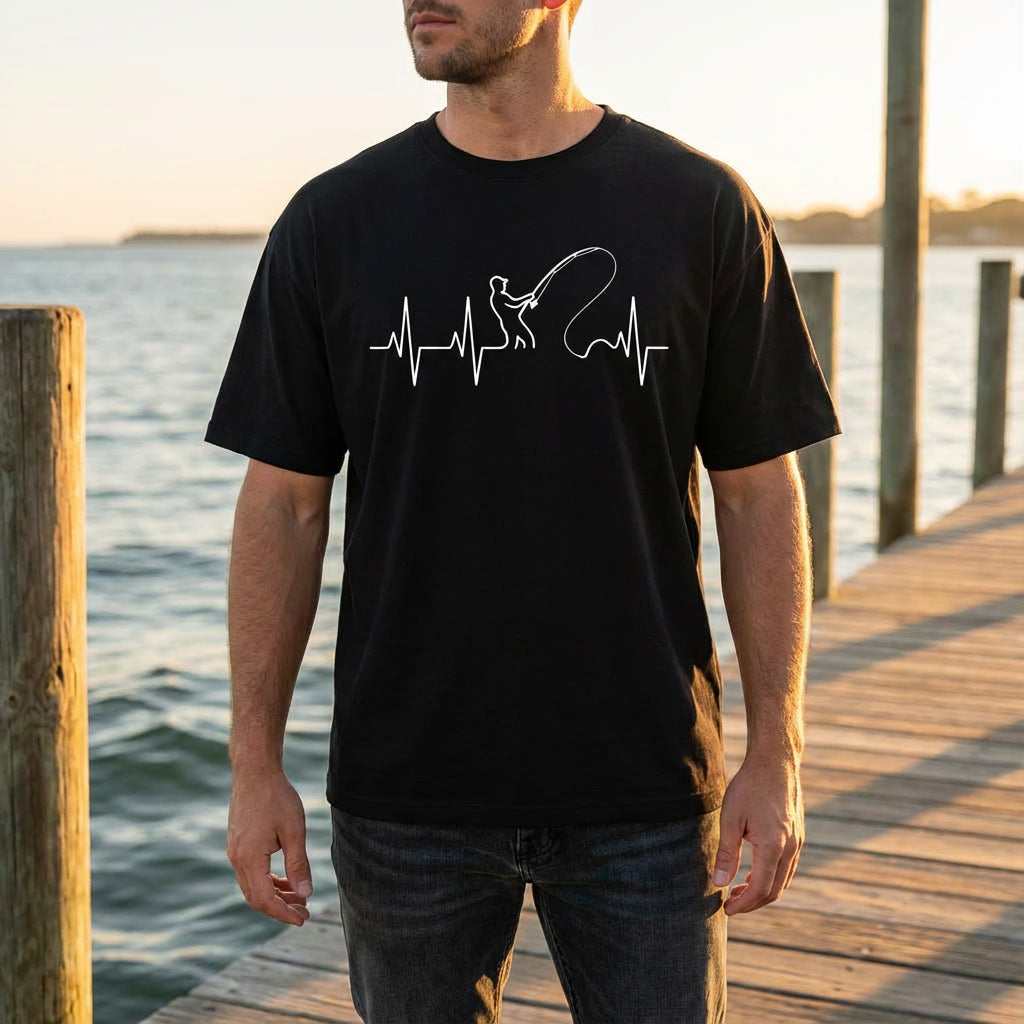 Man wearing a black t-shirt with a white graphic design standing on a wooden dock by water.