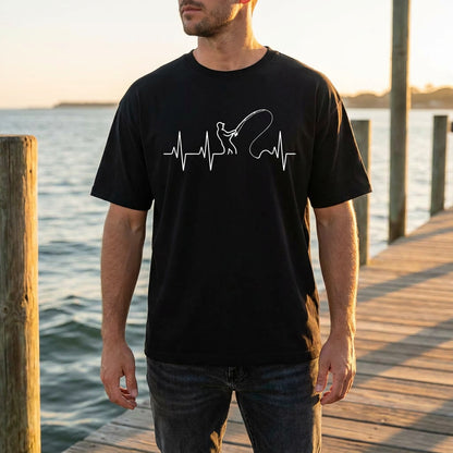 Man wearing a black t-shirt with a white graphic design standing on a wooden dock by water.
